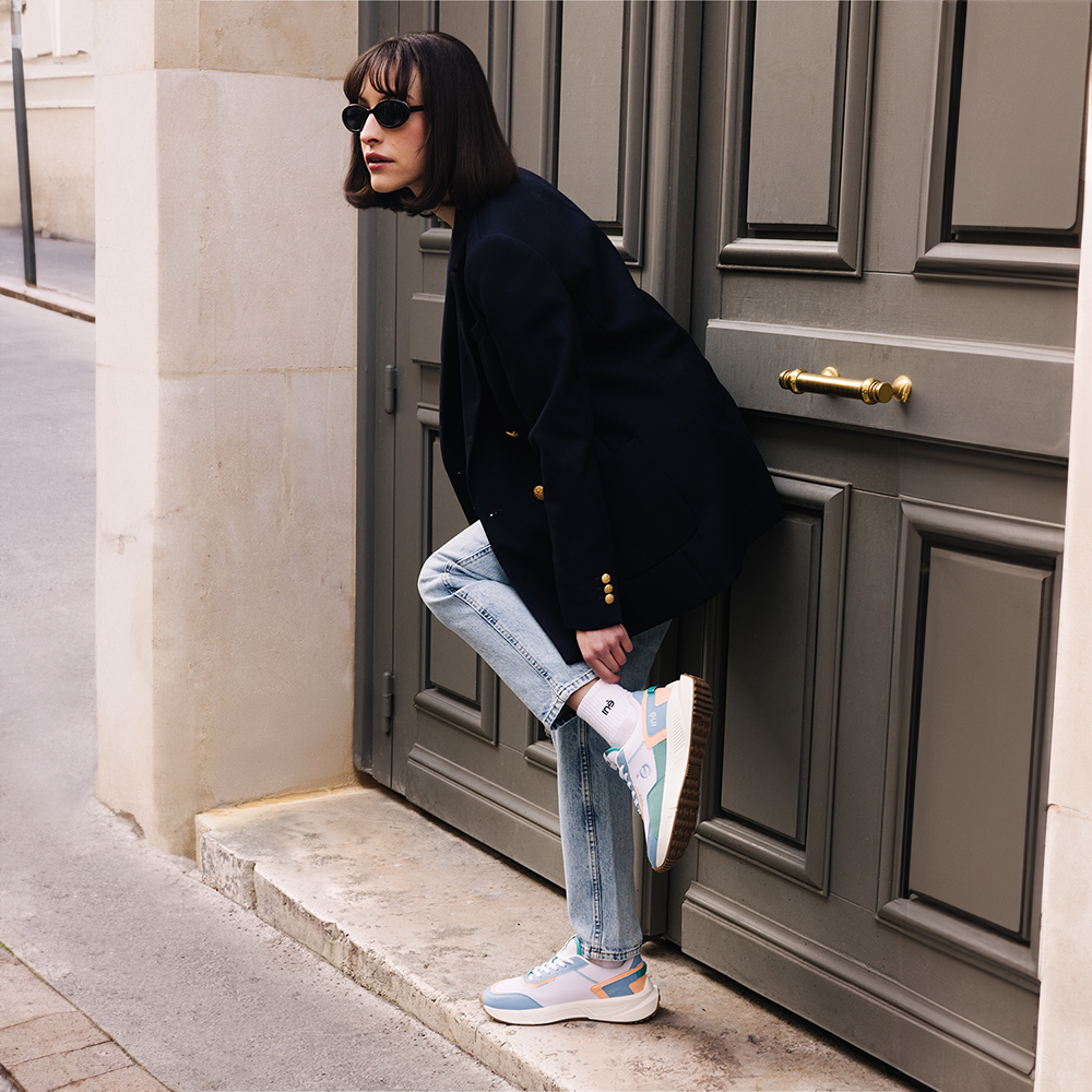 Femme essayant des baskets de la marque iné, vegan et unisexes de couleur corail et bleu pastel