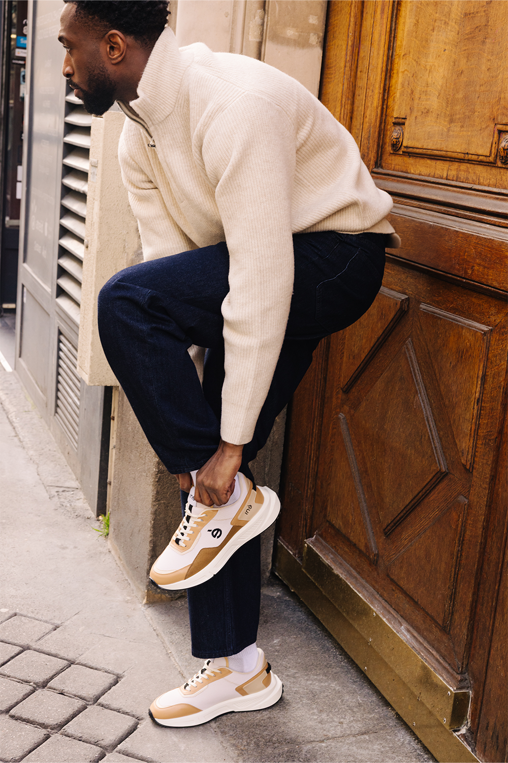 Homme portant des baskets vegan unisexes beige et noir de la marque iné, disponibles du 36 au 46