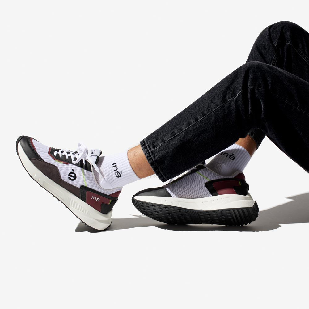 Homme portant des baskets vegan unisexes bordeaux et noir de la marque iné, disponibles du 36 au 46
portées avec jean noir