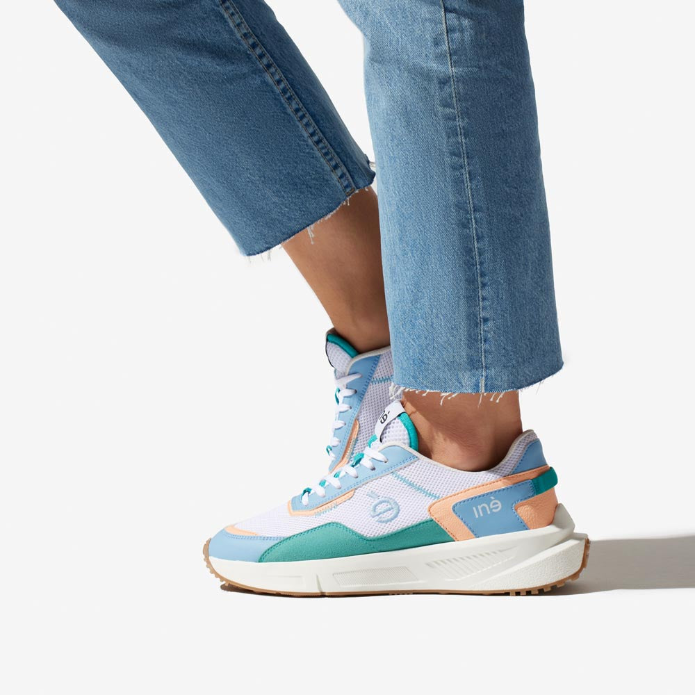 Baskets vegan unisexes corail et bleu pastel de la marque iné, disponibles du 36 au 46 portées avec un jean