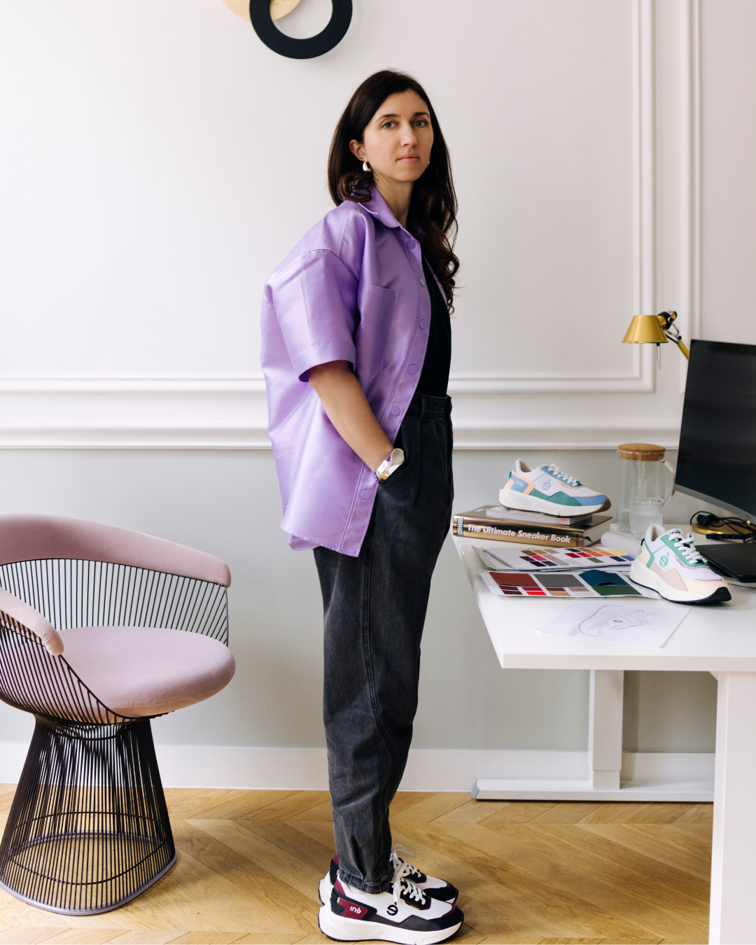 Audrey Delanoë pose dans son bureau parisien, elle porte des sneakers vegan et unisexes de sa marque iné