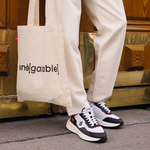 Homme portant des sneakers vegan unisexes bordeaux et noir et pantalon beige de la marque iné, disponibles du 36 au 46