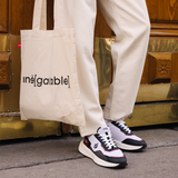 Homme portant des sneakers vegan unisexes bordeaux et noir et pantalon beige de la marque iné, disponibles du 36 au 46