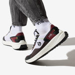 Personne portant des sneakers vegan unisexes bordeaux et noir de la marque iné, disponibles du 36 au 46 et un jean noir
