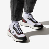 Personne portant des sneakers vegan unisexes bordeaux et noir de la marque iné, disponibles du 36 au 46 et un jean noir