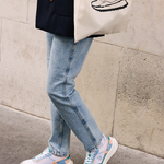 Femme portant des sneakers vegan unisexes corail et bleu pastel et un tote bag