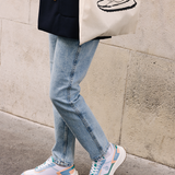 Femme portant des sneakers vegan unisexes corail et bleu pastel et un tote bag