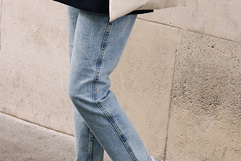Femme portant des sneakers vegan unisexes corail et bleu pastel et un tote bag