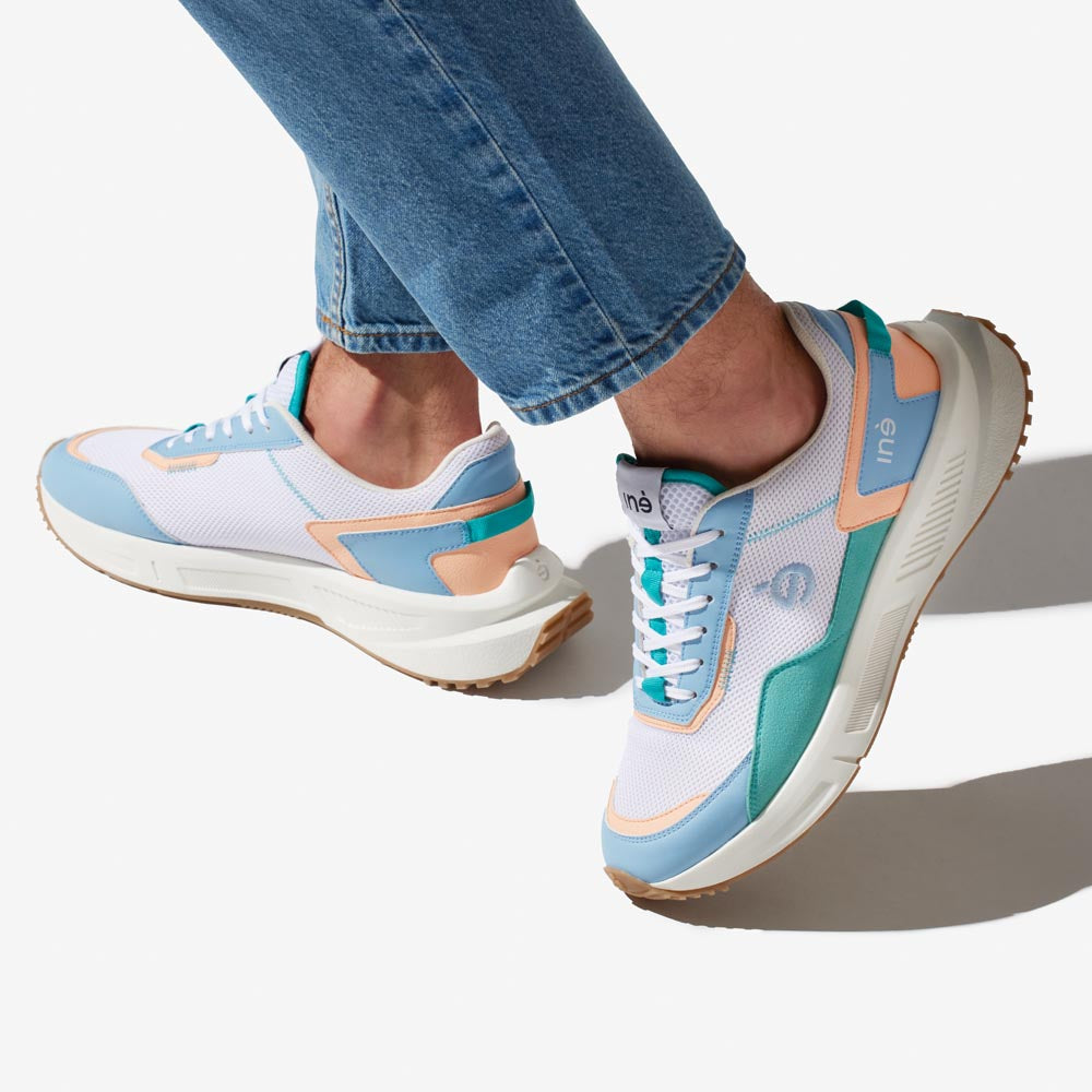 Homme portant des sneakers vegan unisexes corail et bleu pastel et un jean