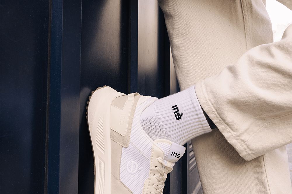 Homme portant des baskets crème et jaune et un pantalon beige de la marque iné, unisexes, disponibles du 36 au 46