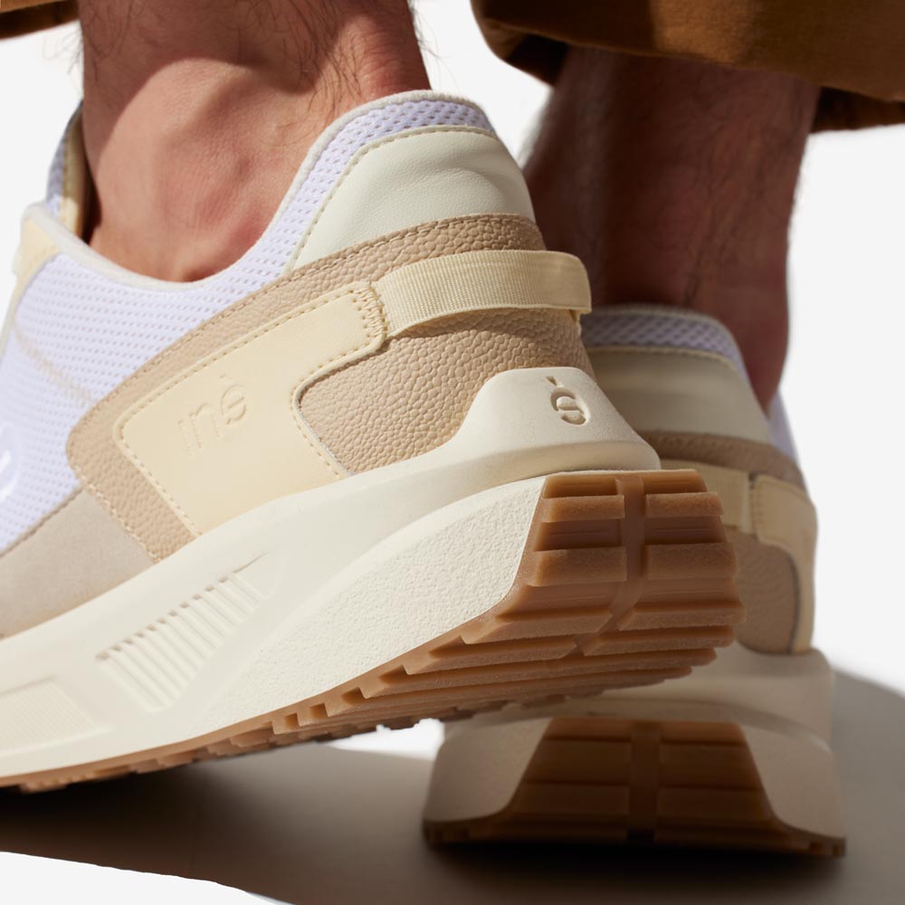 Homme portant des sneakers crème et jaune de la marque iné, disponibles du 36 au 46
