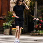 Femme portant des sneakers orange et vert de la marque iné, disponibles du 36 au 46 devant un fleuriste 