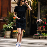 Femme portant des sneakers orange et vert de la marque iné, disponibles du 36 au 46 devant un fleuriste 